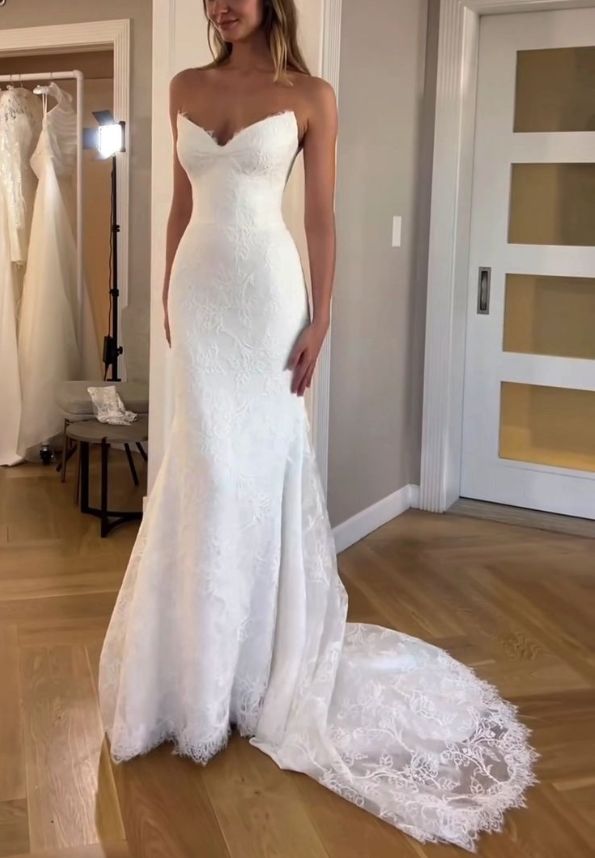 a woman in a white wedding dress standing next to some dresses on a wooden floor