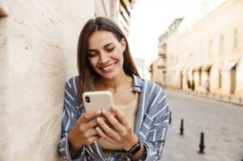 a woman is looking at her phone while leaning against a wall in an alleyway