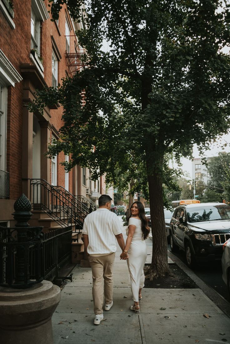 a couple walking down the sidewalk holding hands