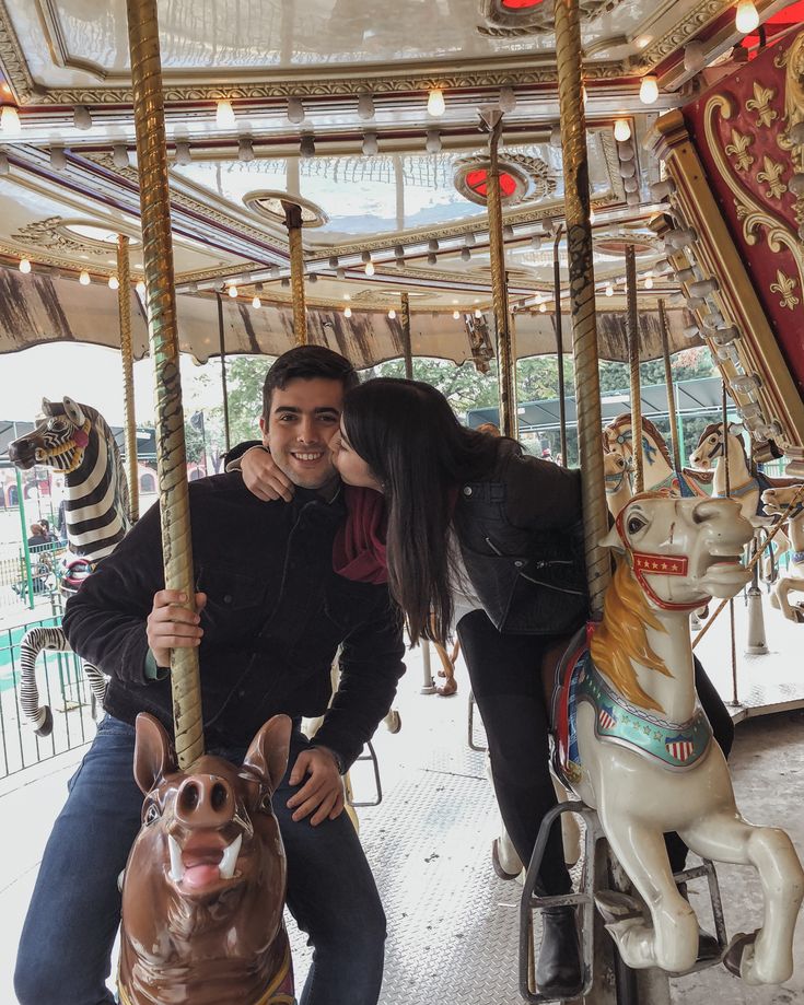 a man and woman kissing on a merry go round with a dog in the foreground