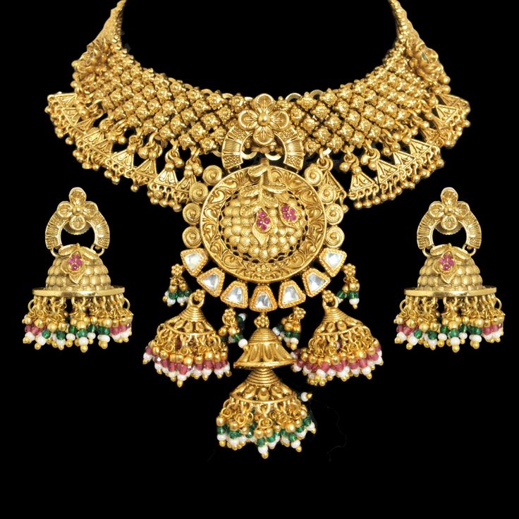 Temple Jewelry Set inspired by Amrapali India's rich heritage. This exquisite piece is a testament to the artistry of temple jewelry, adorned with intricate details and antique finishes. Reflecting the traditions of South India, it combines elegance with timeless charm. Created by Amrapali, a renowned name in jewelry, this necklace features Kundan elements for added opulence. Perfect for special occasions, it celebrates the cultural legacy of India and adds a touch of regal beauty to any ensembl Ornate Kundan Bridal Necklace For Festive Occasions, Festive Ornate Kundan Bridal Necklace, Heavy Ornate Necklace For Festive Occasions, 22k Gold Cutdana Jewelry For Puja, Heavy Temple Jewelry Sets In Yellow Gold, Heavy Antique Gold Necklace For Festive Occasions, Heavy Antique Gold Temple Jewelry Necklace, Ceremonial Yellow Gold Meenakari Bridal Necklace, Heavy Yellow Gold Temple Jewelry Sets