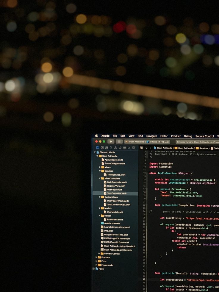 a laptop computer sitting on top of a desk in front of a dark cityscape