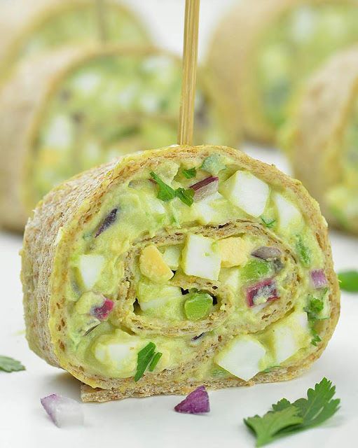 an avocado roll is cut in half and placed on a white plate with green garnishes