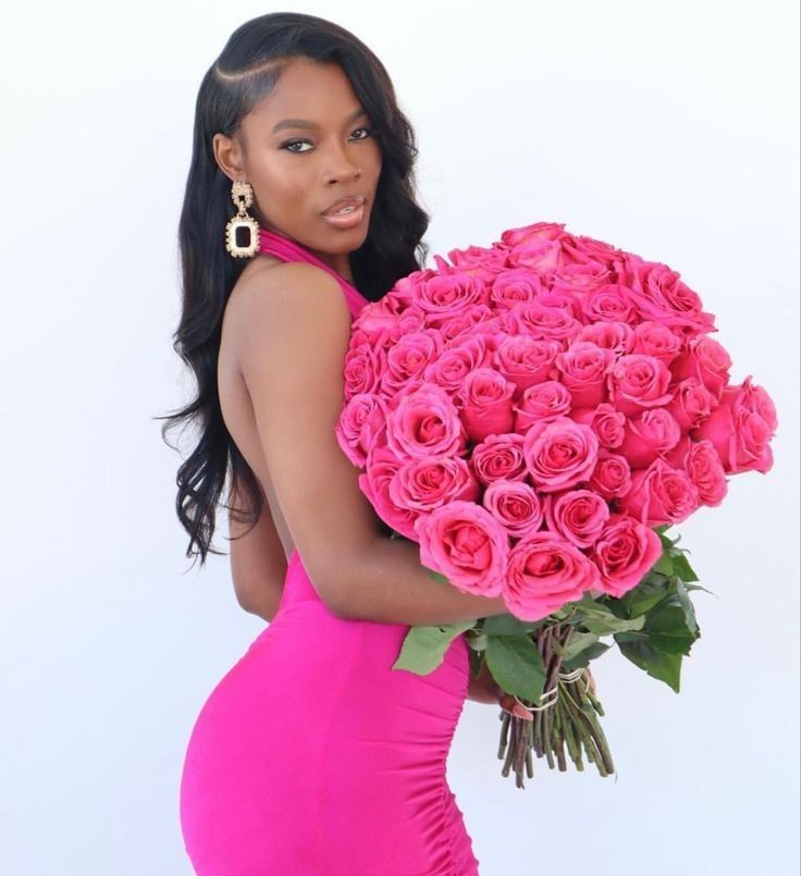 a woman in a pink dress holding a large bouquet of roses