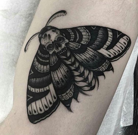 a black and white photo of a moth on the arm with an intricate pattern around it