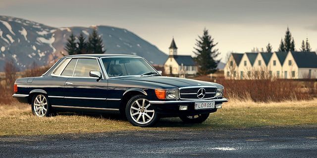 a black mercedes benz parked on the side of the road in front of some houses