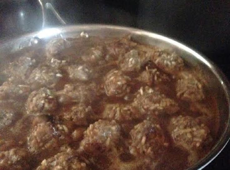 meatballs are cooking in a pan on the stove