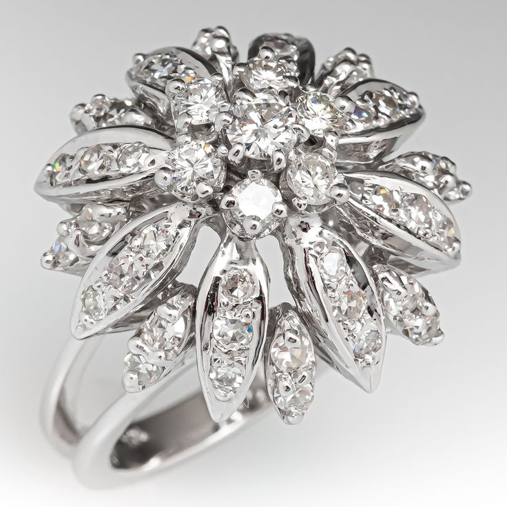 This captivating vintage floral cocktail ring features a pierced design and is centered with a cluster setting accented with seven (7), prong set, round brilliant cut diamonds. The petal shaped settings are accented with forty (40), bead/prong set, round single cut diamonds. The ring measures 19.5mm at the top, rises 14.0mm above the finger, tapering to 2.8mm wide and 1.8mm thick at the base of the shank. This ring is currently a size 6. Two of the diamonds are chipped but nothing distracting. Cluster Flower Ring With Prong Setting For Anniversary, Formal Fine Jewelry Flower Ring With Diamond Accents, Elegant Cluster Flower Ring With Diamond Accents, Elegant Flower Ring With Diamond Cluster, Formal Flower Ring With Brilliant Cut Diamond, Elegant Cluster Flower Ring With Halo Setting, Formal Flower Shaped Diamond Ring With Prong Setting, Flower Shaped Cluster Ring With Brilliant Cut Diamond, Formal Flower-shaped Diamond Ring With Rose Cut