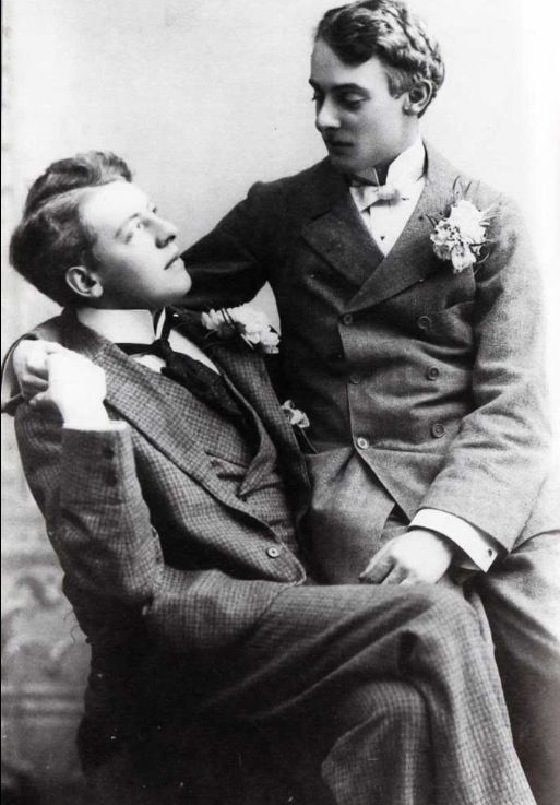 an old black and white photo of a man in a suit sitting next to a woman