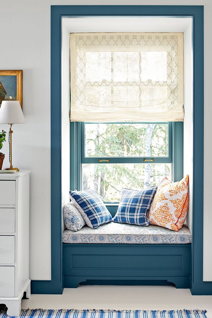 a window seat in the corner of a room with blue walls and white trim on it