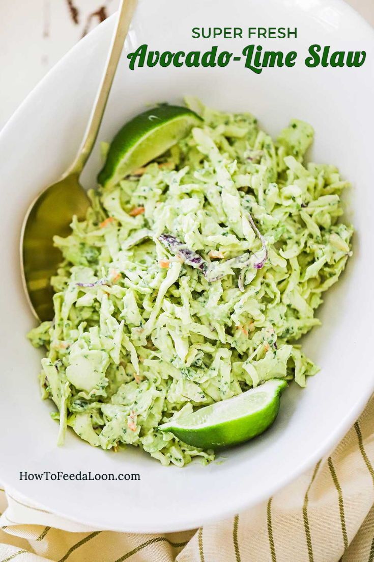 a white bowl filled with guacamole and lime wedges next to a spoon