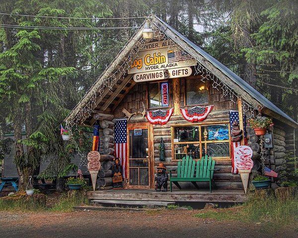 a small building with flags on the front and side of it that is surrounded by trees