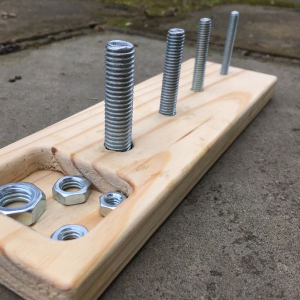 screws and nuts are placed on a wooden board with bolts in the bottom half