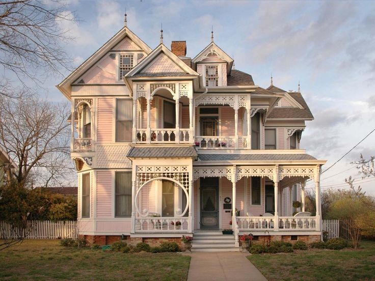 an old victorian house with white trim on the front and side porchs, along with two balconies