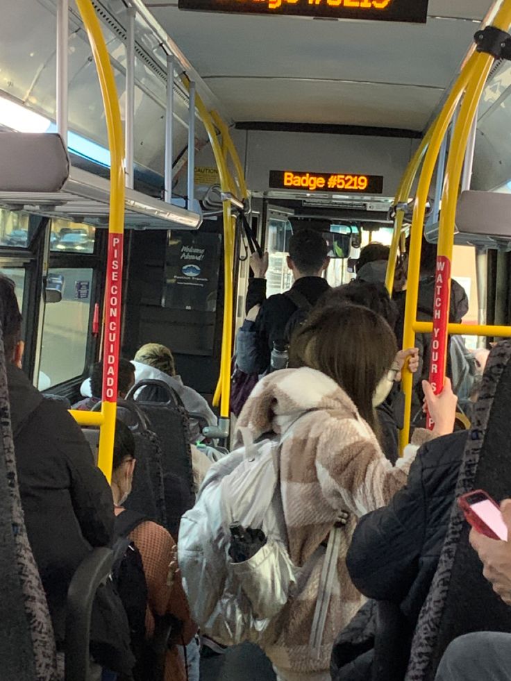 many people are sitting on the bus and one person is holding a cell phone