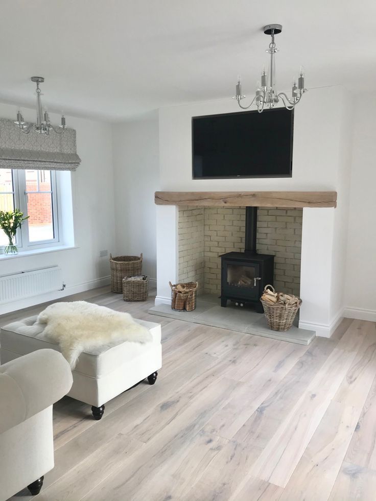 a living room with white furniture and a flat screen tv on the wall above an open fire place