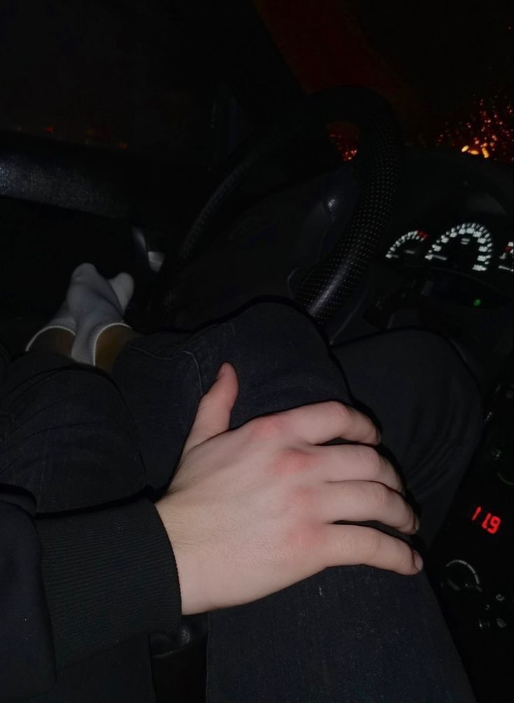 a person in a car with their hand on the steering wheel