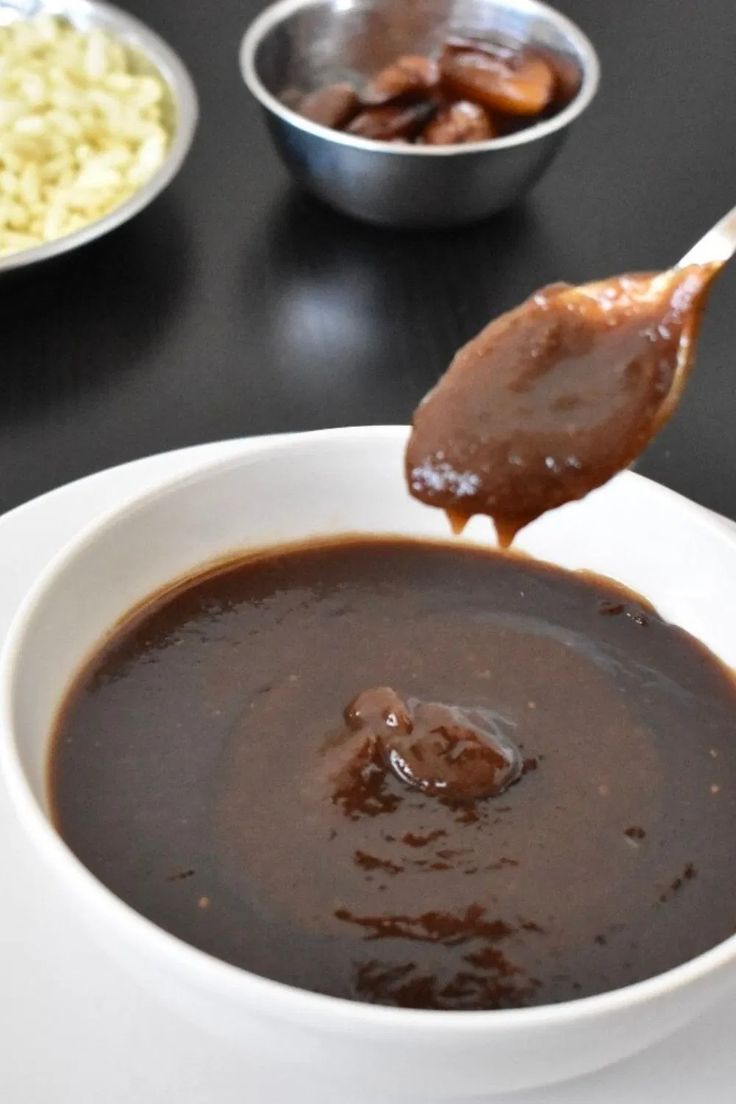 a spoon with some food in it sitting on a plate next to other plates and bowls