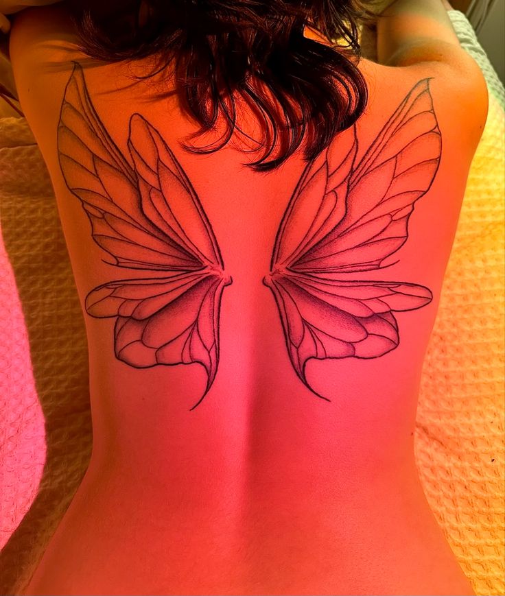 a woman's back with a butterfly tattoo on it