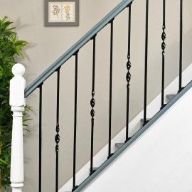 a white stair case next to a green plant in a room with gray walls and black railings