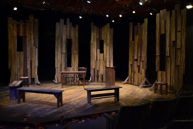 an empty stage with chairs and tables in front of wooden partitions on the wall