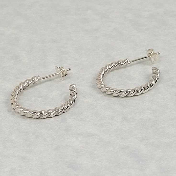 A classic earring design that never goes out of style, but with a twist! Double strands of sterling silver wire are twisted together to form these medium-size twisted hoop earrings that would be an elegant addition to any jewelry collection. Hand-wrought from recycled sterling silver, the twisted sterling silver wires are wound together and soldered to form a single 3mm twisted rope strand that is then curved to form the hoop. Hoop earrings are approximately 7/8 inches in diameter, and polished Modern Twist Everyday Earrings, Modern Twist White Gold Hoop Earrings As Gift, White Gold Hoop Earrings With Modern Twist, Modern Twist Silver Hoop Earrings With Ear Wire, Silver Hoop Earrings With A Modern Twist, Silver Spiral Hoop Earrings For Everyday, Everyday Spiral Silver Hoop Earrings, Minimalist Spiral Hoop Earrings In Sterling Silver, Modern Twist Sterling Silver Hoop Earrings For Pierced Ears