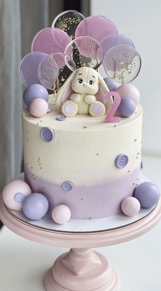 there is a cake decorated with balloons and a teddy bear on top