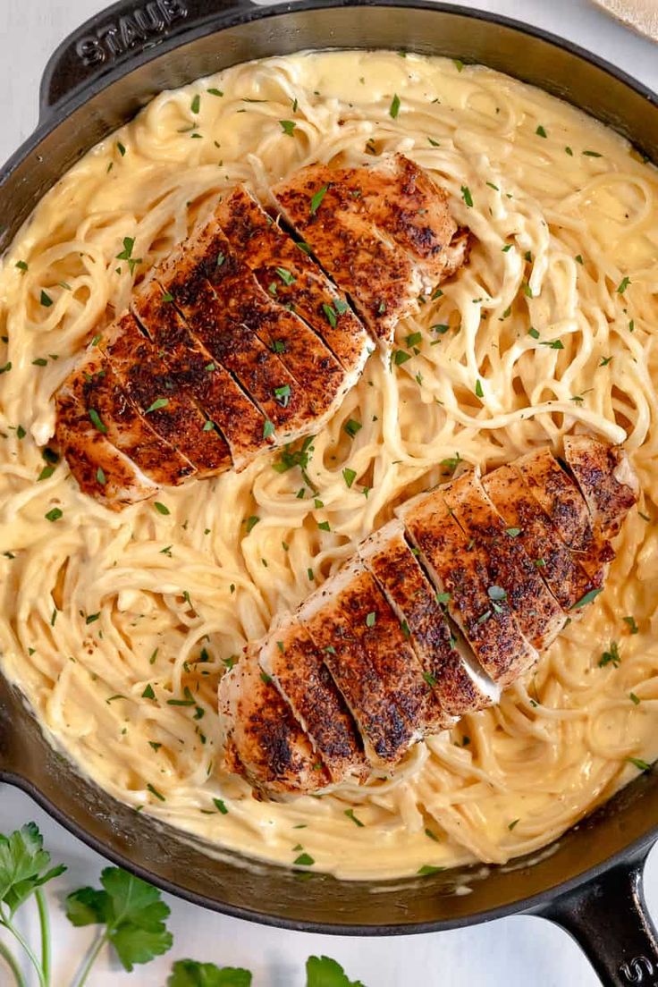 chicken alfredo pasta in a skillet with text overlay that reads, blackened chicken alfredo pasta