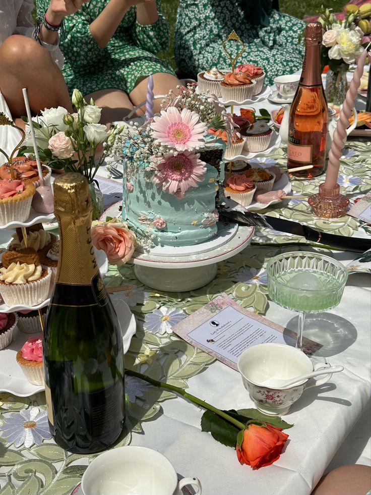 a table topped with cakes and cupcakes on top of a white table cloth