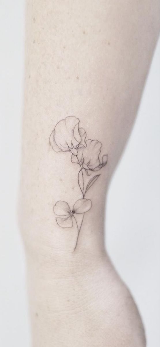 a small flower tattoo on the side of a woman's right leg is shown