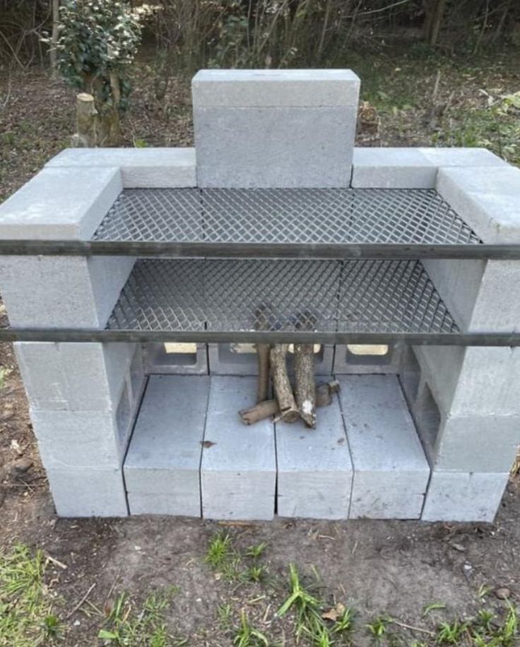 an outdoor fire pit made out of concrete blocks and steel grates, with logs sticking out of it