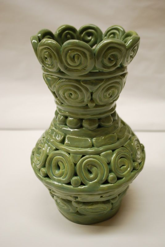 a green vase sitting on top of a white table