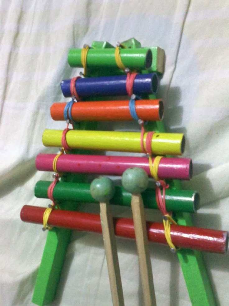 an assortment of colorful wooden toys on a white sheeted surface, with balls and sticks sticking out of them