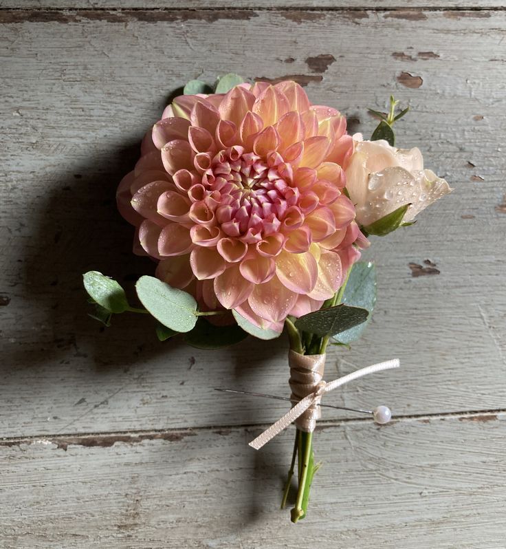 a pink flower is tied to a piece of wood