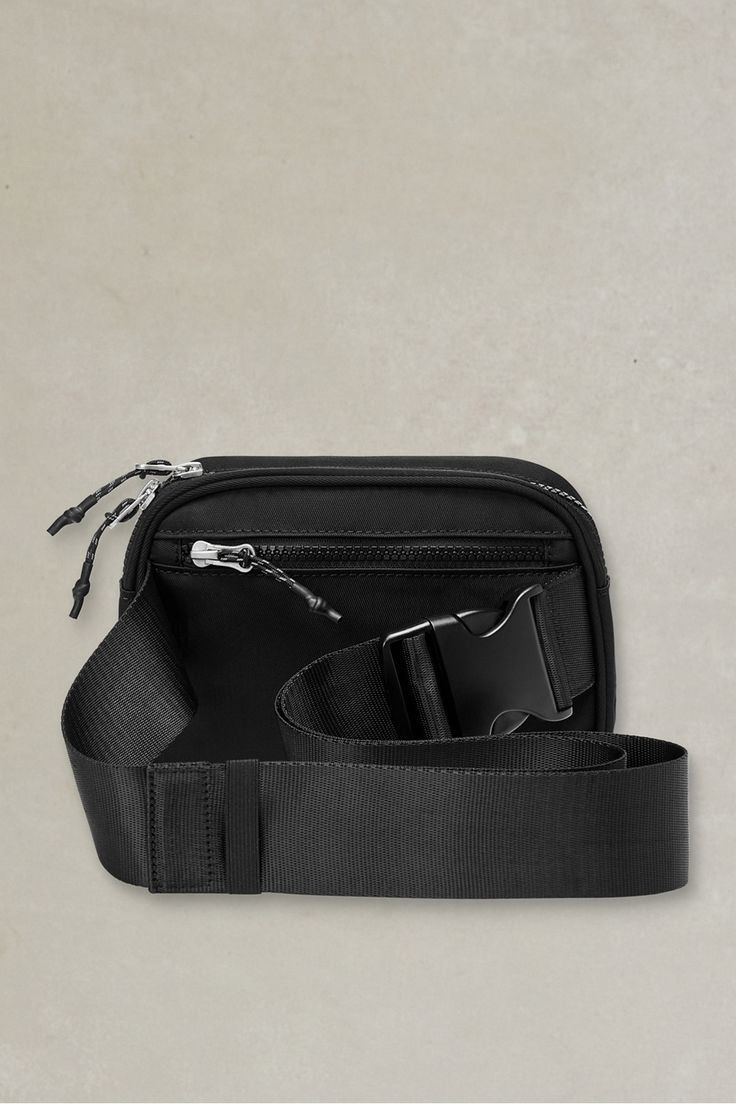 a black camera bag sitting on top of a white wall next to a pair of scissors