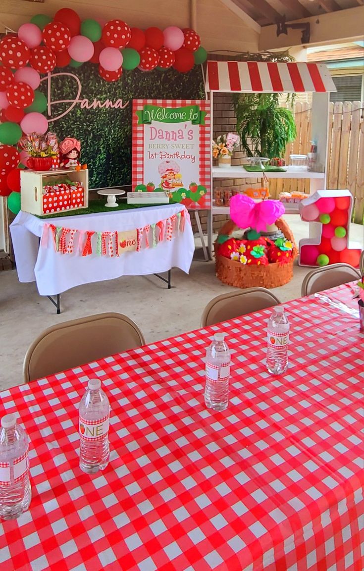 a table with red and white checkered cloths on it is set up for a birthday party