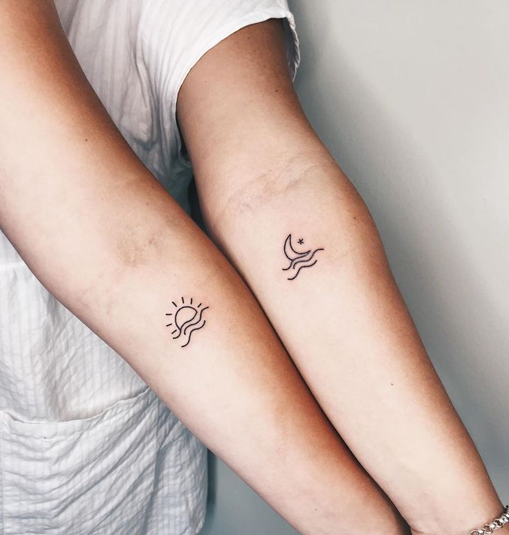 two people with matching tattoos on their arms, one has a sun and the other has a bird