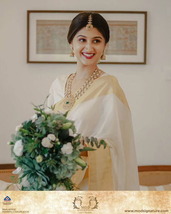 a woman in a white sari holding a bouquet