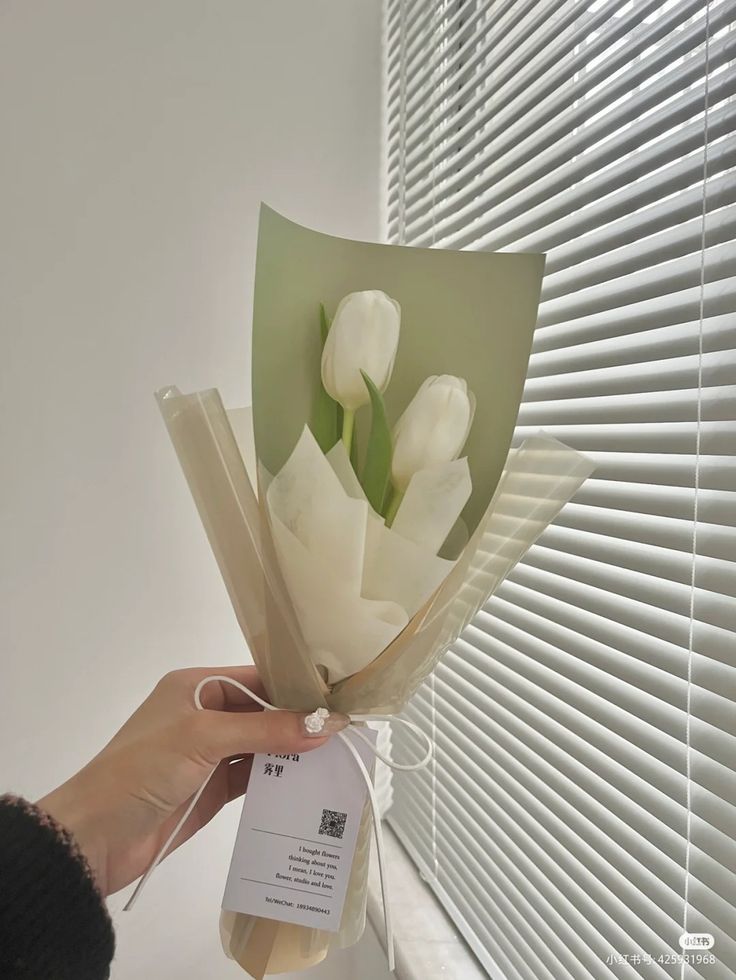 a hand holding a bouquet of white tulips with a price tag on it