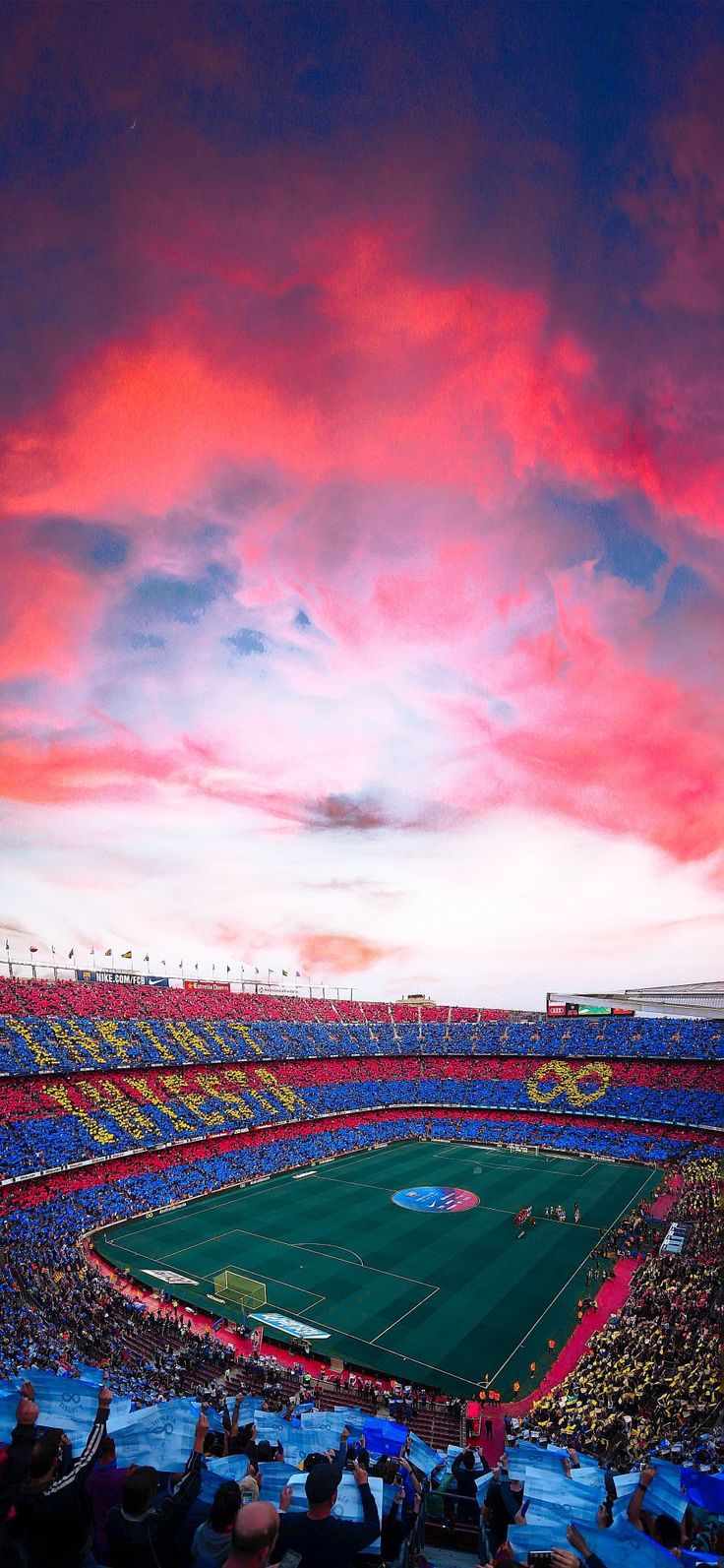 a stadium filled with lots of people watching a soccer game at sunset or sunrise time