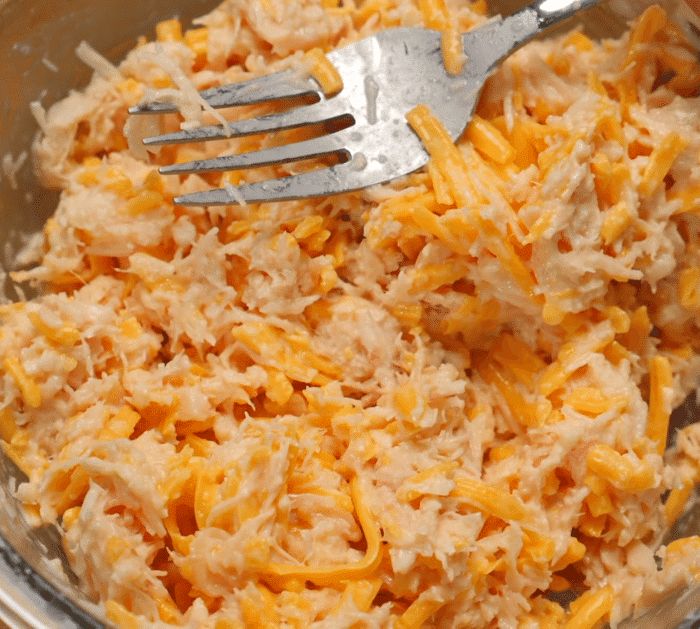 a bowl filled with shredded cheese and a fork