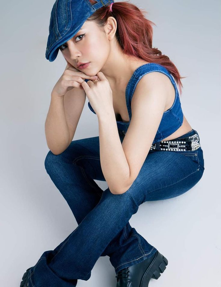 a young woman with red hair wearing jeans and a denim cap is posing for the camera