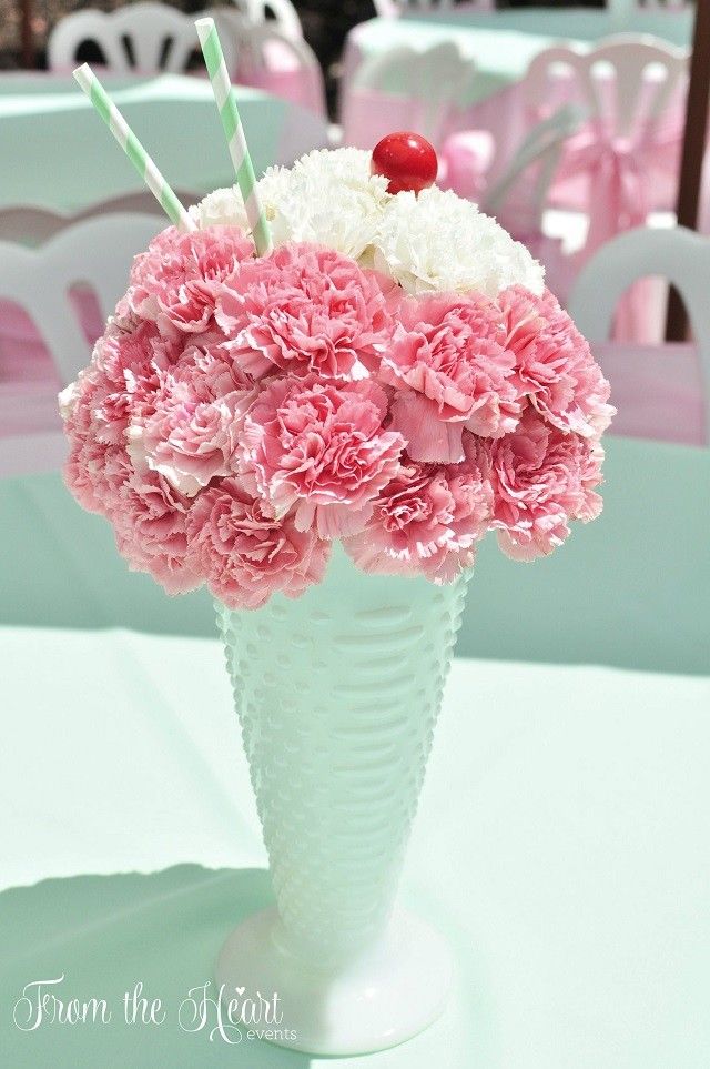 pink and white carnations in a vase with two strawberries on top for decoration