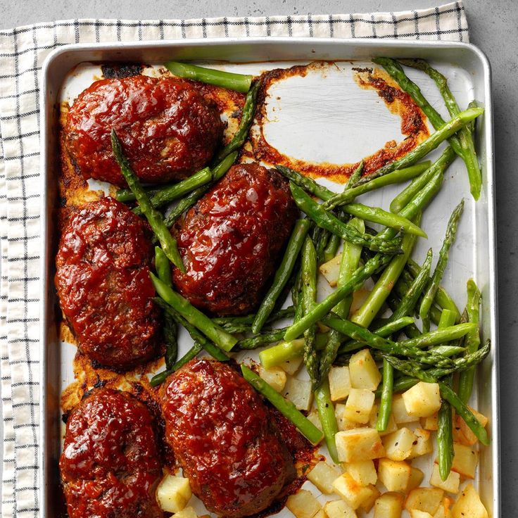 meatballs, green beans and potatoes on a white platter with a red sauce