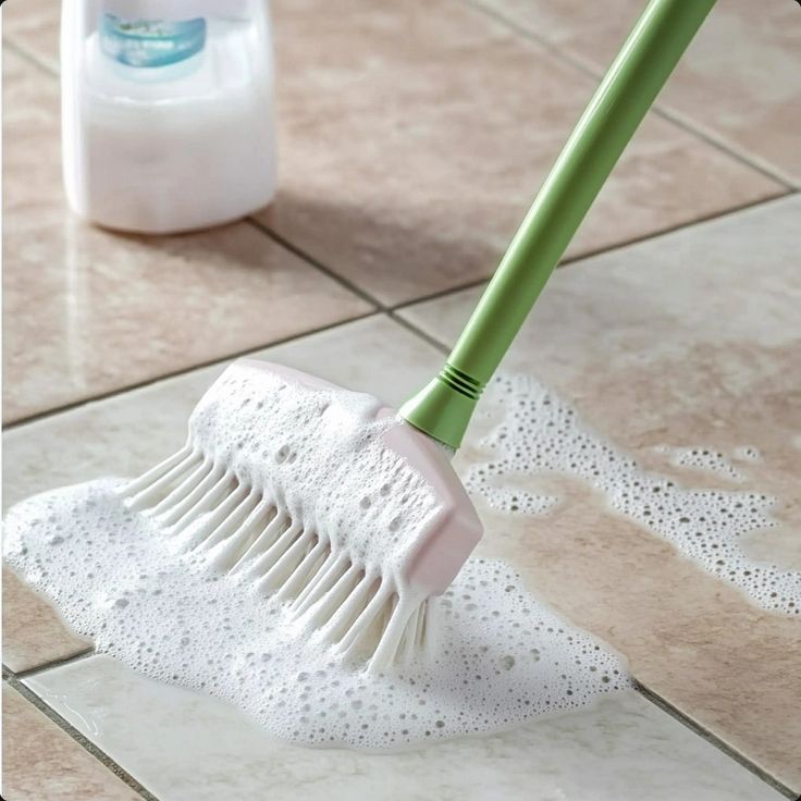 a close up of a cleaning brush on a tile floor next to a bottle of cleaner