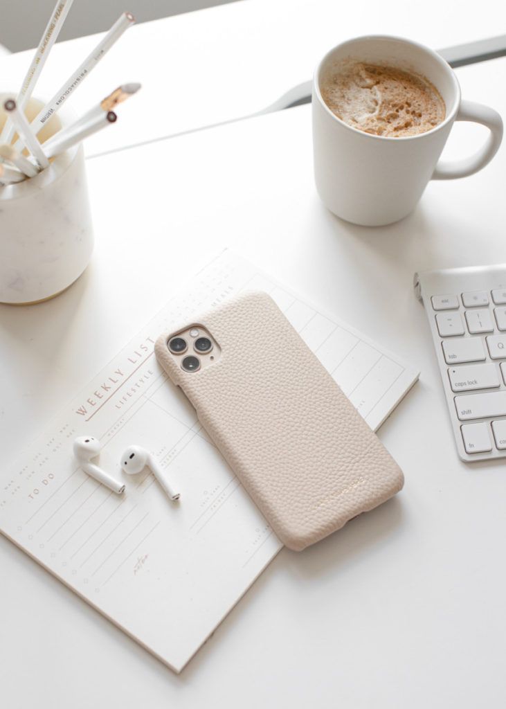 an iphone case sitting on top of a desk next to a cup of coffee and keyboard