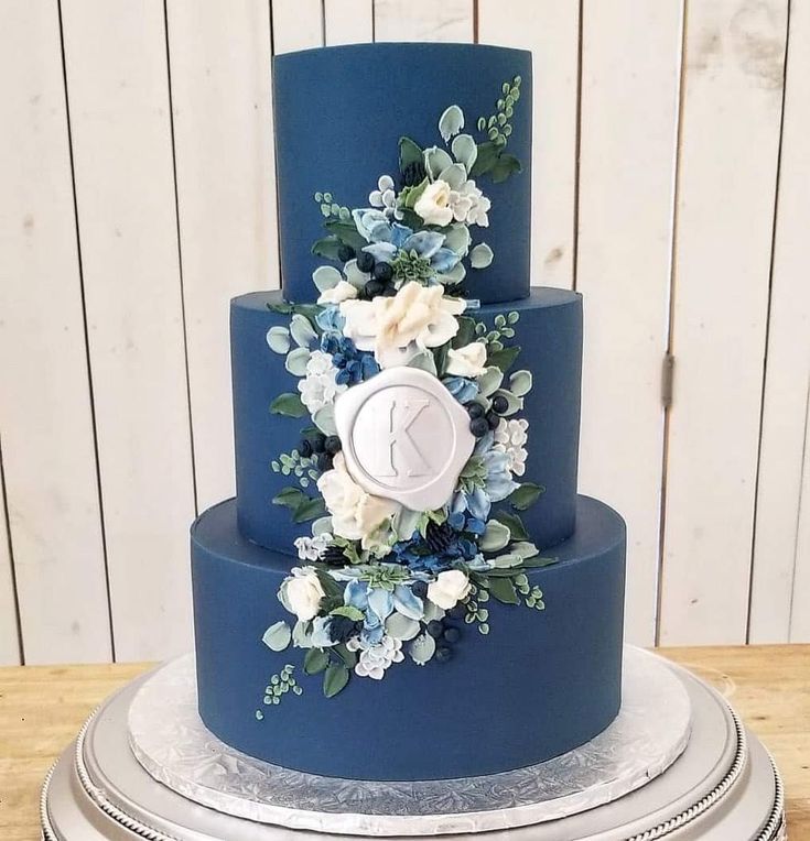 a three tiered blue cake with white and blue flowers