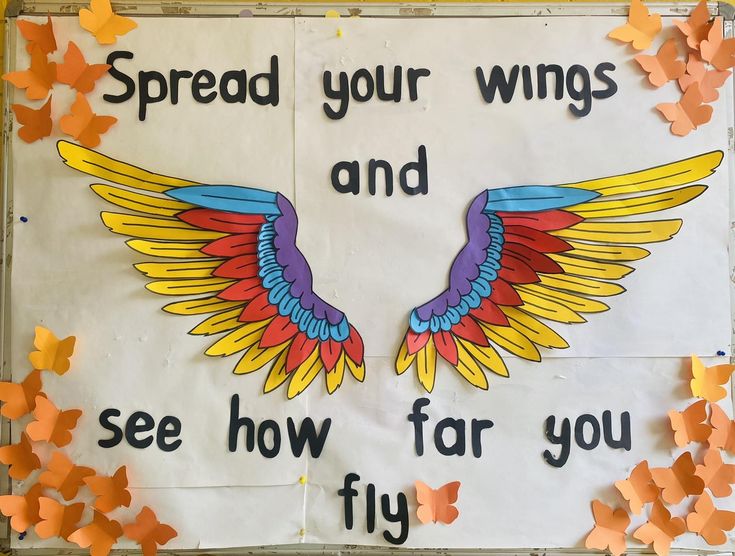 a bulletin board with colorful wings and words written on the front, surrounded by butterflies