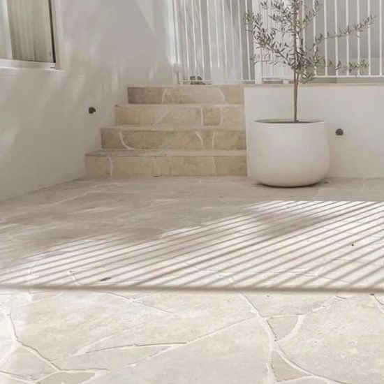 a white planter sitting on top of a stone floor next to a stair case