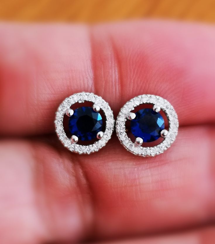 These Halo Blue Sapphire Stud Earrings are one of a kind. They look fabulous and beautiful when worn. This pair of Round Diamond Cut Blue Sapphire with Halo of Round shape simulated diamonds is excellent cut, Bright White D Color, and VVS1 Purity. These Earrings feature push backs for secure locking. Comes with a perfect Gift Box, Ideal for Gifting. A great gift for all occasions for your loved ones. Ultra-luxurious and sophisticated this dramatic diamonds Stimulant Halo earrings studs are made Blue Halo Cubic Zirconia Earrings, Blue Halo Design Earrings For Anniversary, Blue Round Earrings For Anniversary, Formal Blue Halo Earrings, Blue Halo Earrings For Formal Occasions, Sapphire Earrings With Halo Setting For Anniversary, Sapphire Earrings With Halo Setting As Gift, Sapphire Earrings With Halo Setting For Gift, Blue Halo Design Earrings As Gift